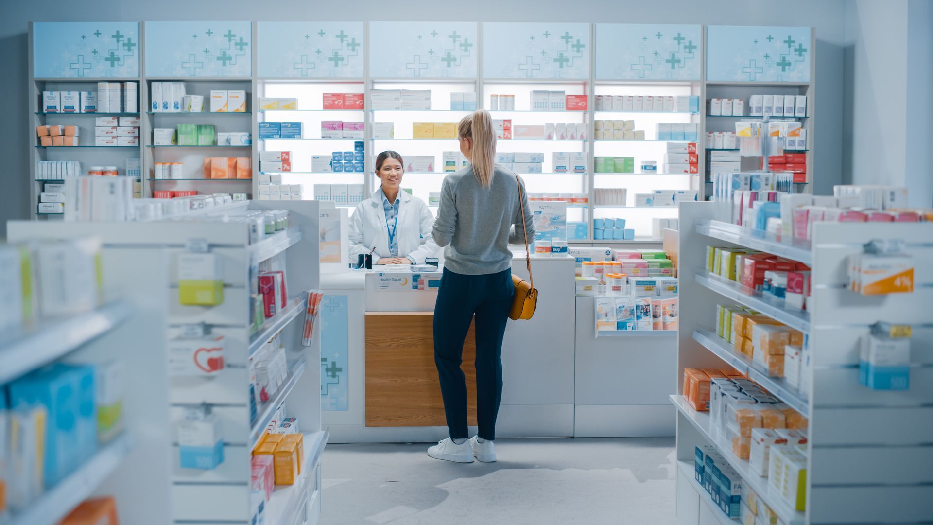 A woman is standing at a counter in a pharmacy.