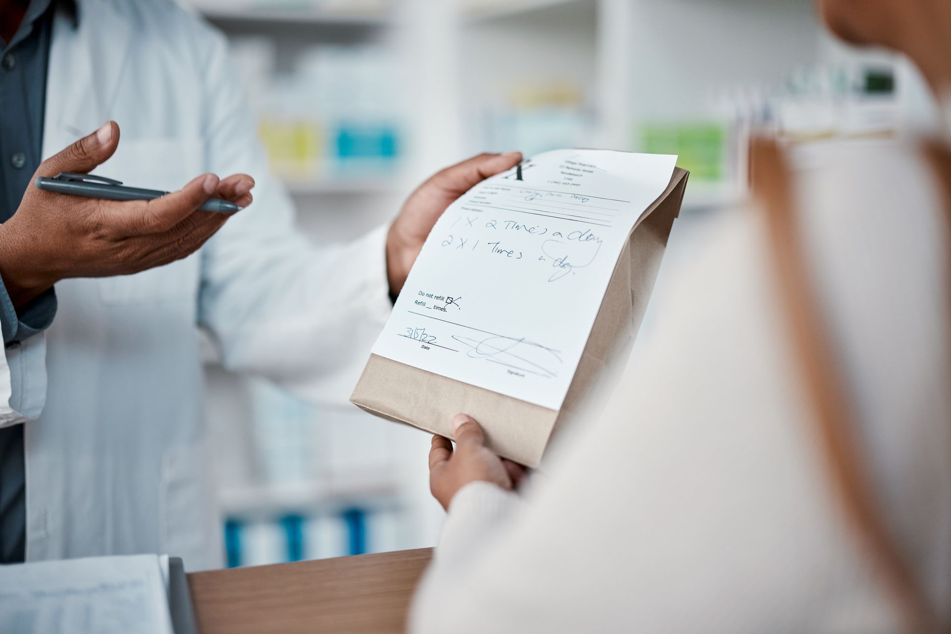 A woman is giving a prescription to a pharmacist in a pharmacy.