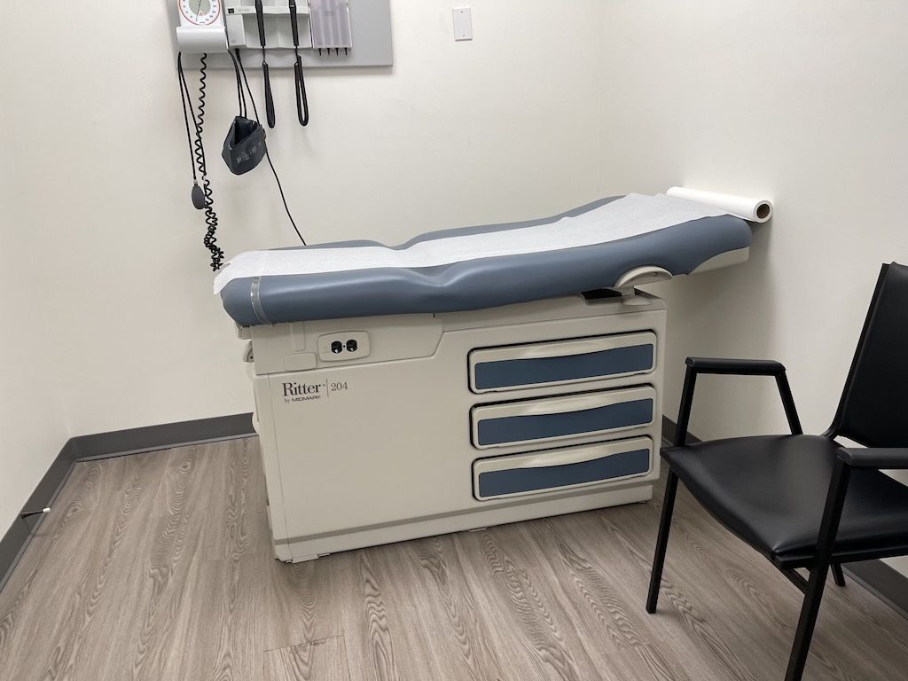 A doctor 's office with a examination table and a chair.