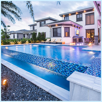 Luxurious backyard with pool, two-story house, outdoor seating, and blue mosaic tile accents.