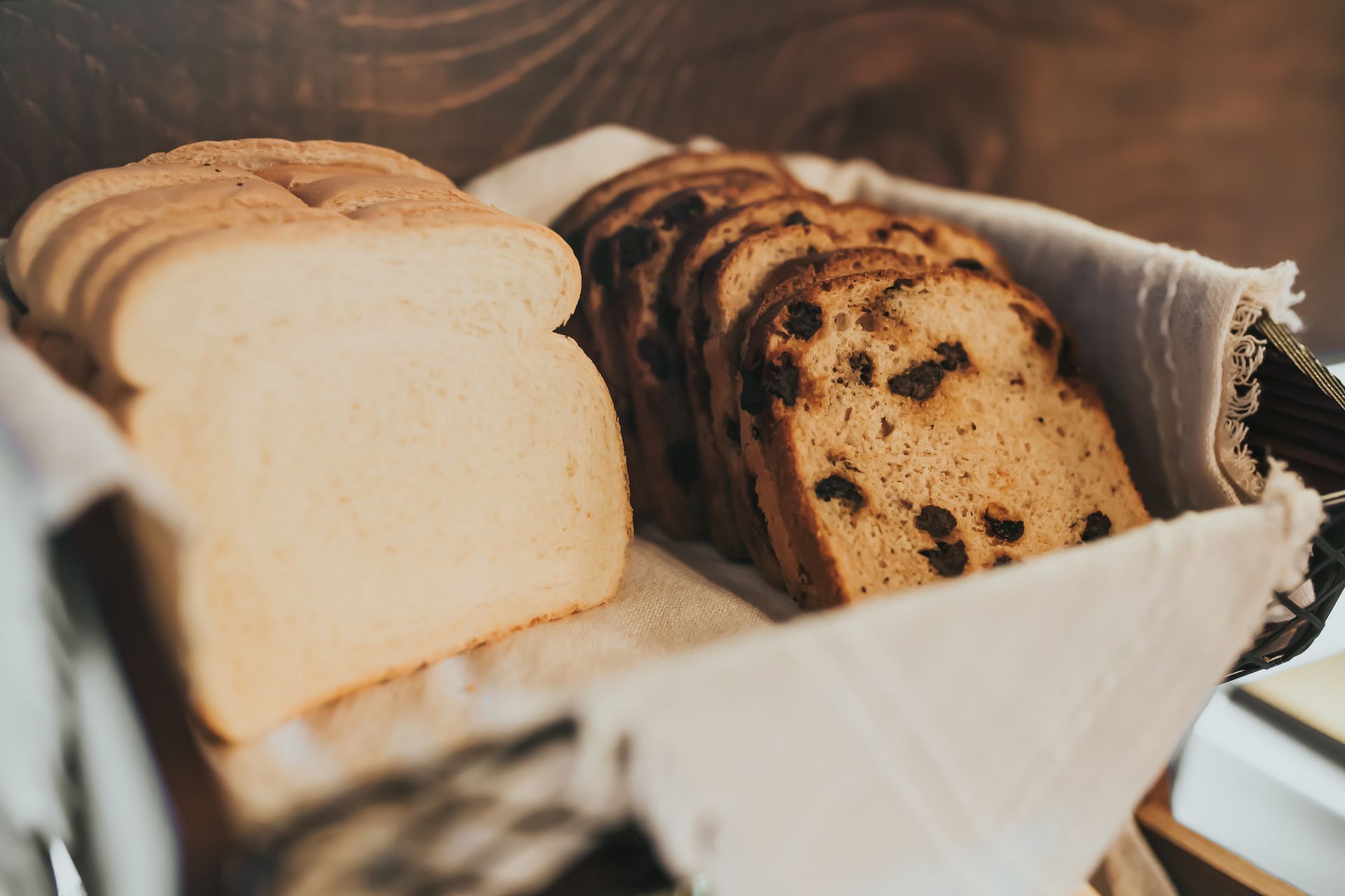Basket of sliced white bread and raisin bread.