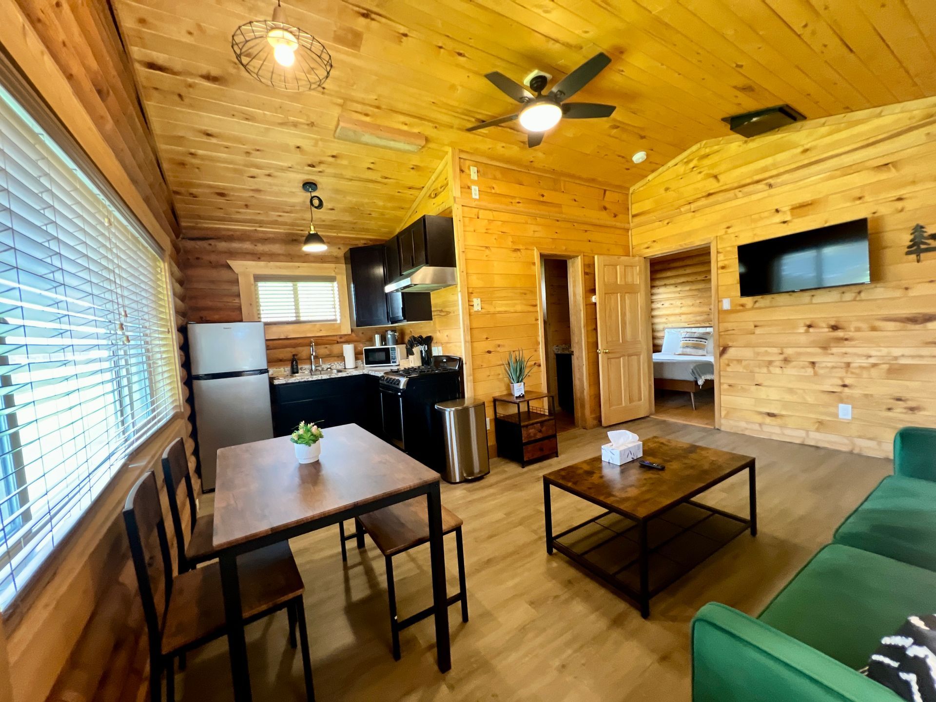 Cozy cabin interior with a dining area, kitchen, and living room, featuring wood paneling.