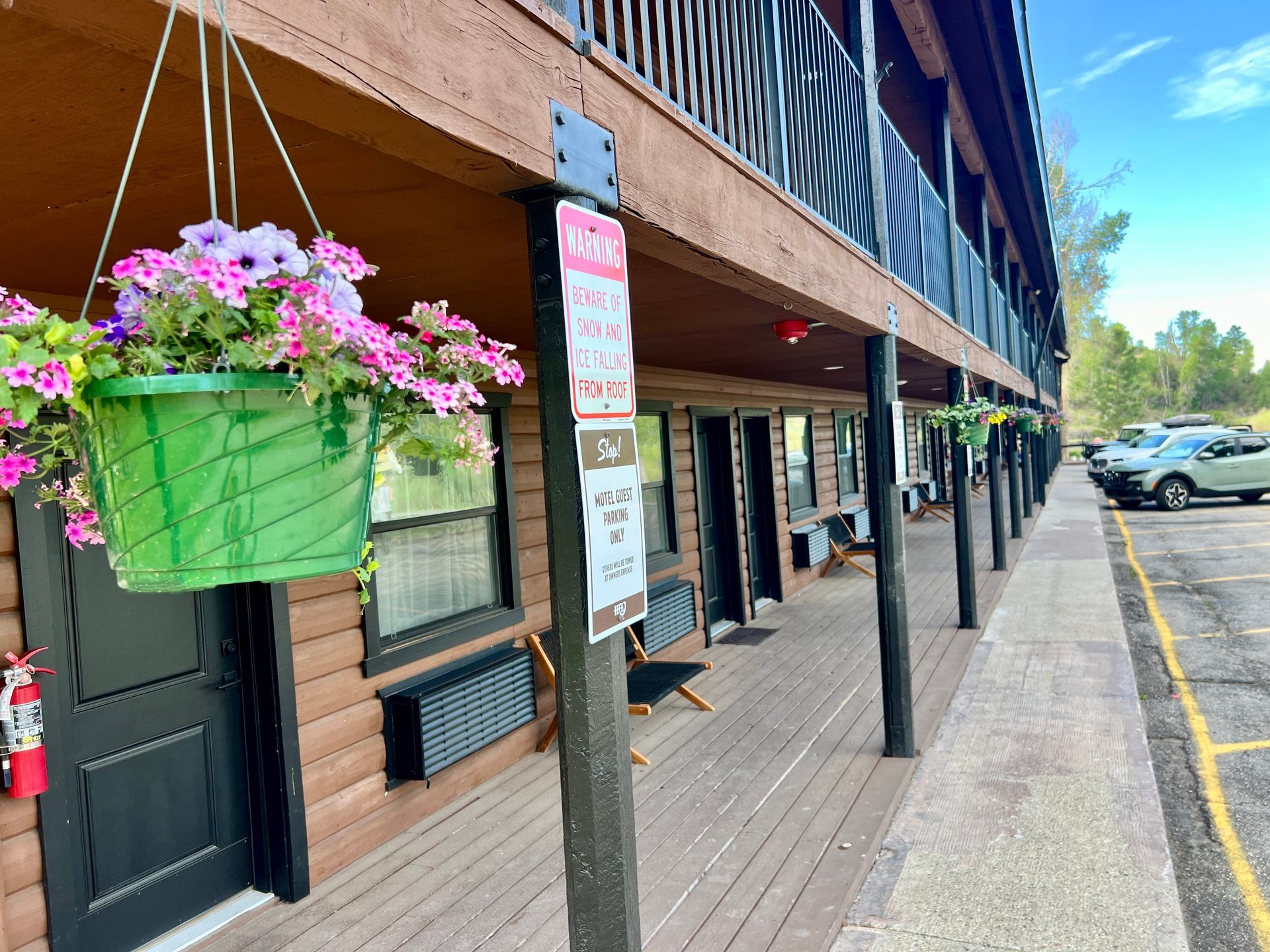 Motel exterior with a hanging flower basket, brown siding, and a covered walkway.