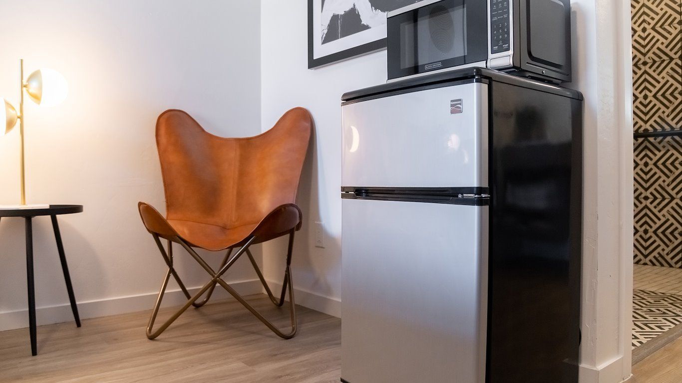 A small room with a brown leather butterfly chair, mini-fridge, and a microwave.