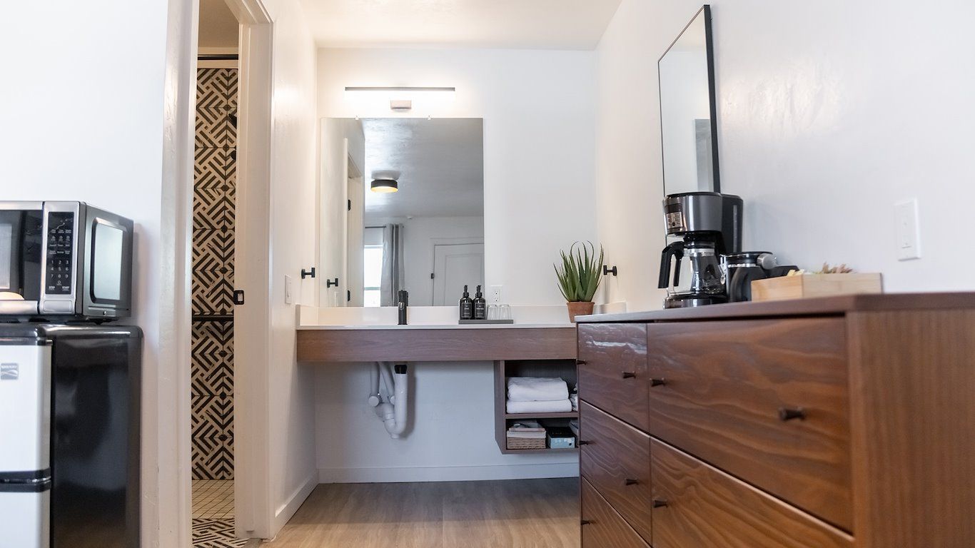 Bathroom with white walls, a floating sink, and a wooden dresser; a microwave is visible.