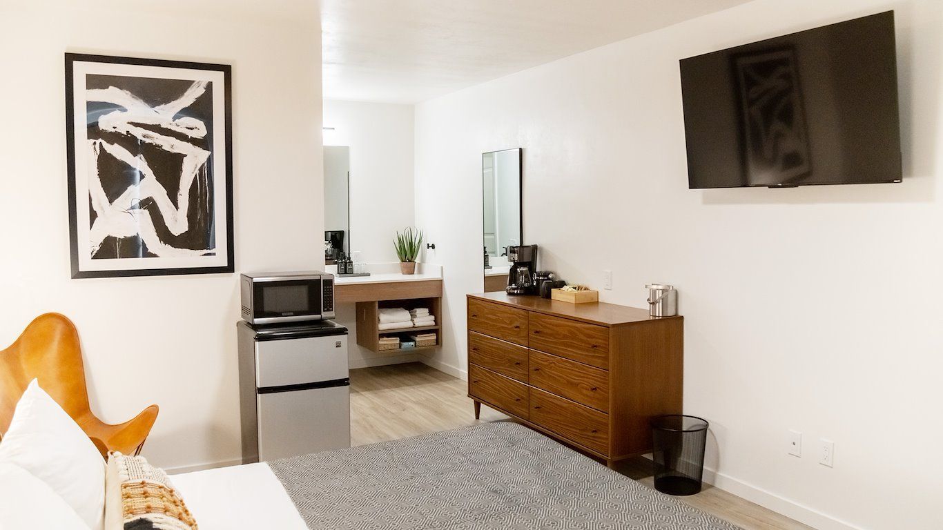 Hotel room with a bed, dresser, TV, artwork, microwave, and sink.