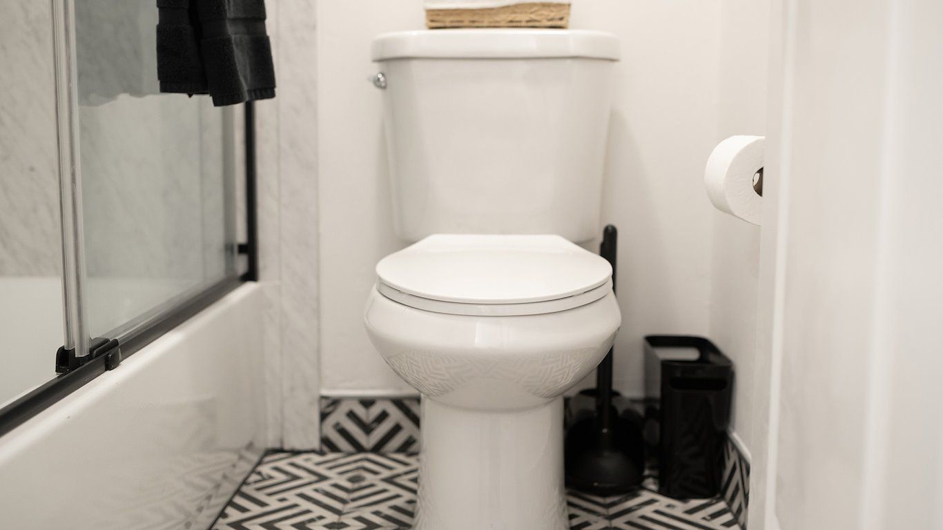 White toilet in a bathroom with black and white patterned floor tiles.
