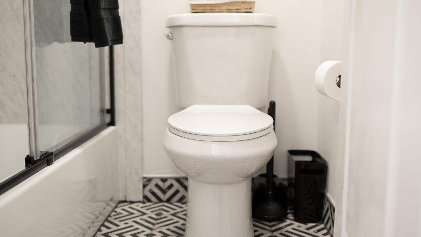 A white toilet in a bathroom with black and white patterned floor tiles.