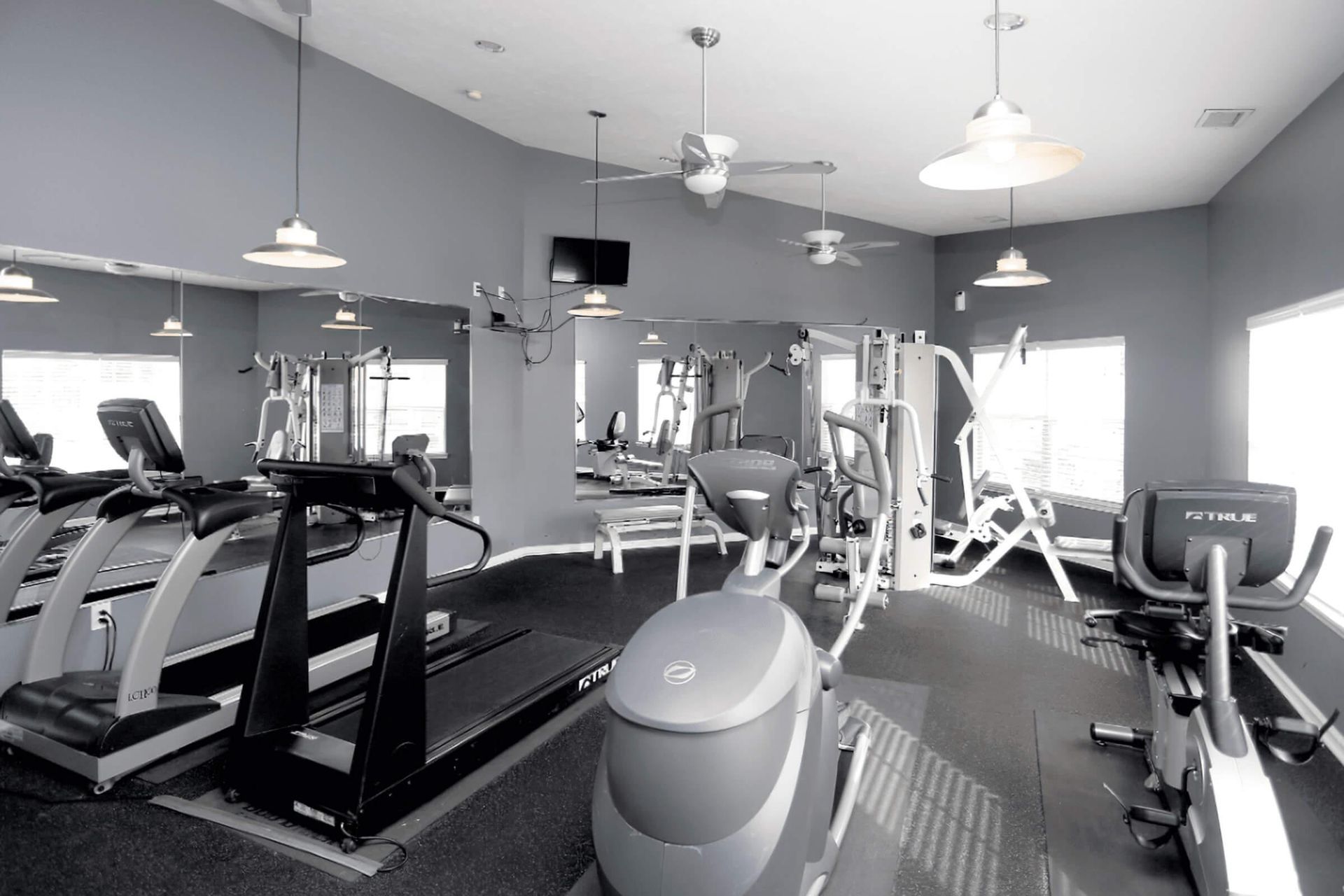 A black and white photo of a gym with treadmills and exercise bikes at The 85Twenty.