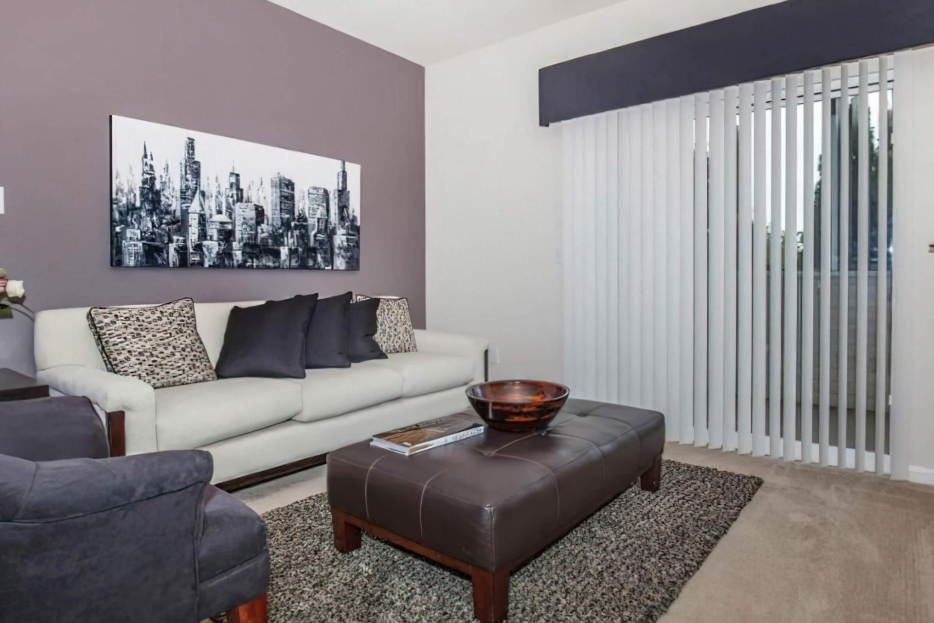 Echo Ridge apartment living room with luxury interior like modern sofa, coffee table, wall art, and spacious balcony window.