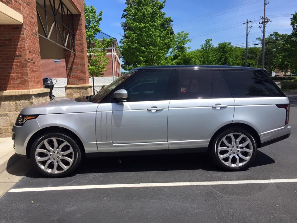Silver Range Rover parked outside a brick building on a sunny day.