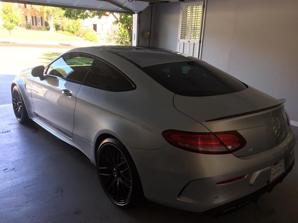 Silver Mercedes-Benz coupe parked inside a garage. The car has black wheels and a rear spoiler.