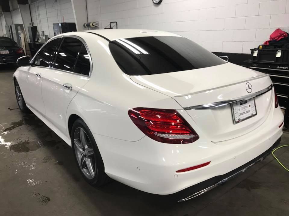 White Mercedes sedan with tinted windows parked inside a garage.