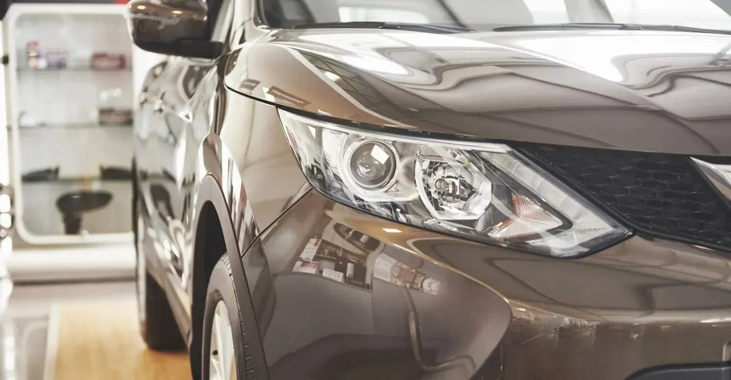 Brown SUV's front corner, headlight detail. Showroom setting, reflections on the shiny body.