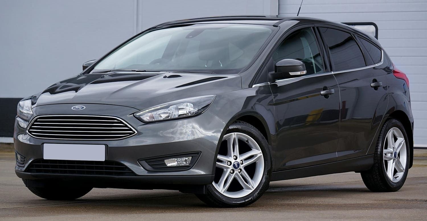 Gray Ford Focus hatchback parked in front of a building.