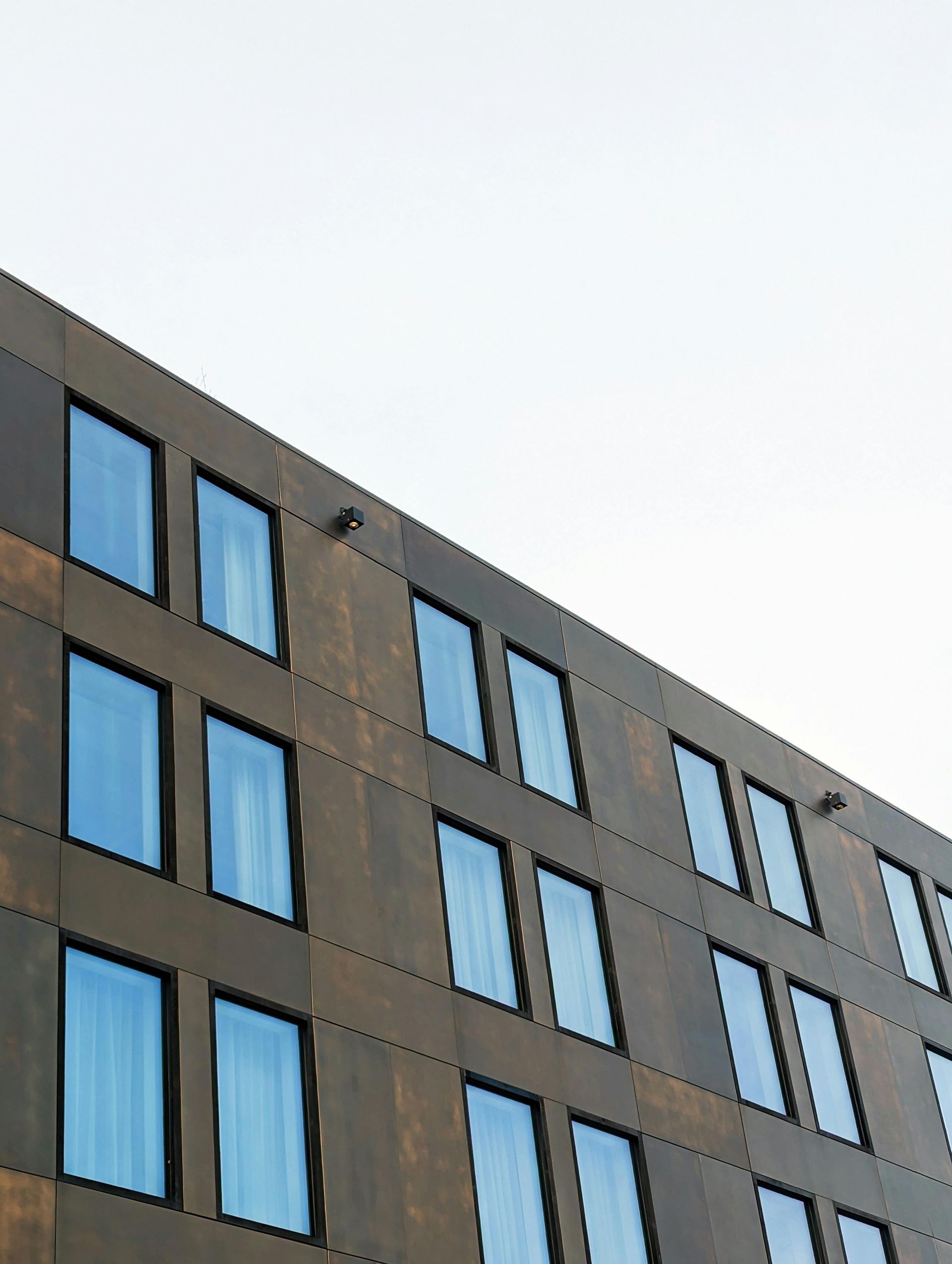 Brown building facade with rectangular windows, blue sky.