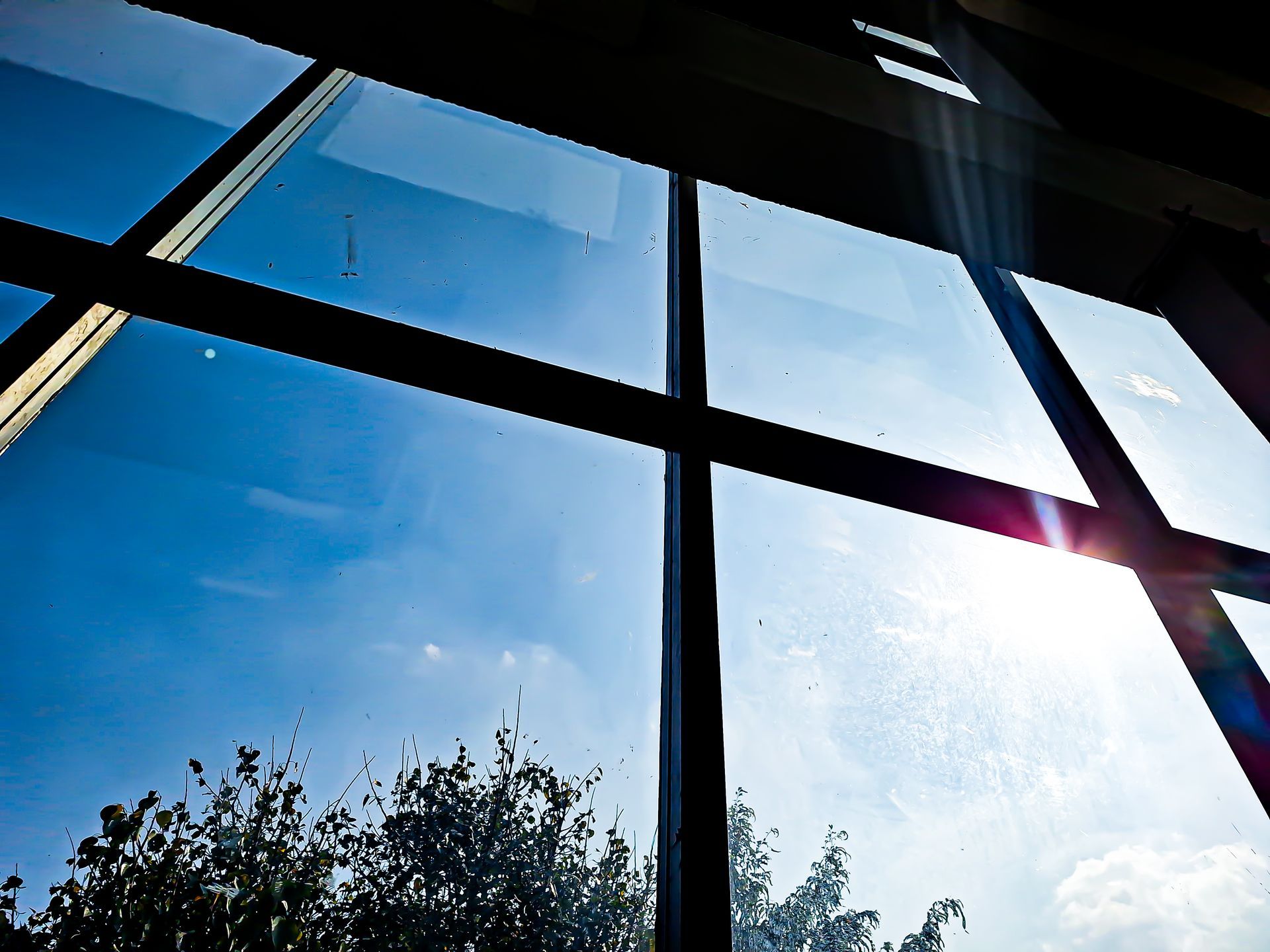 Bright blue sky seen through a multi-paned window, sun shining.
