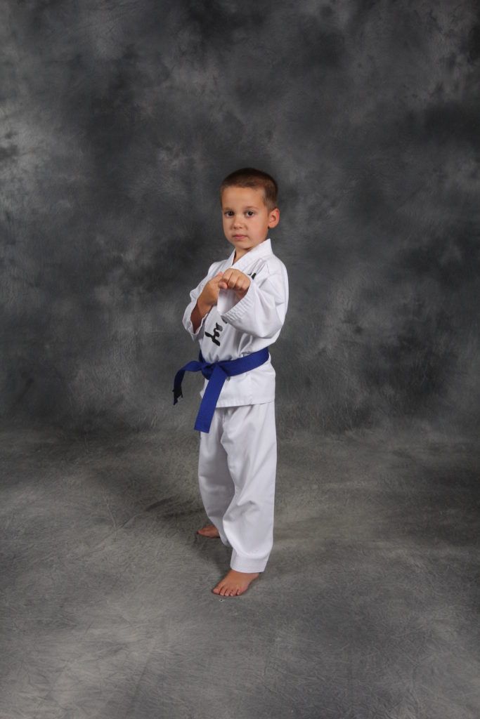 A young boy in a white karate uniform with a blue belt