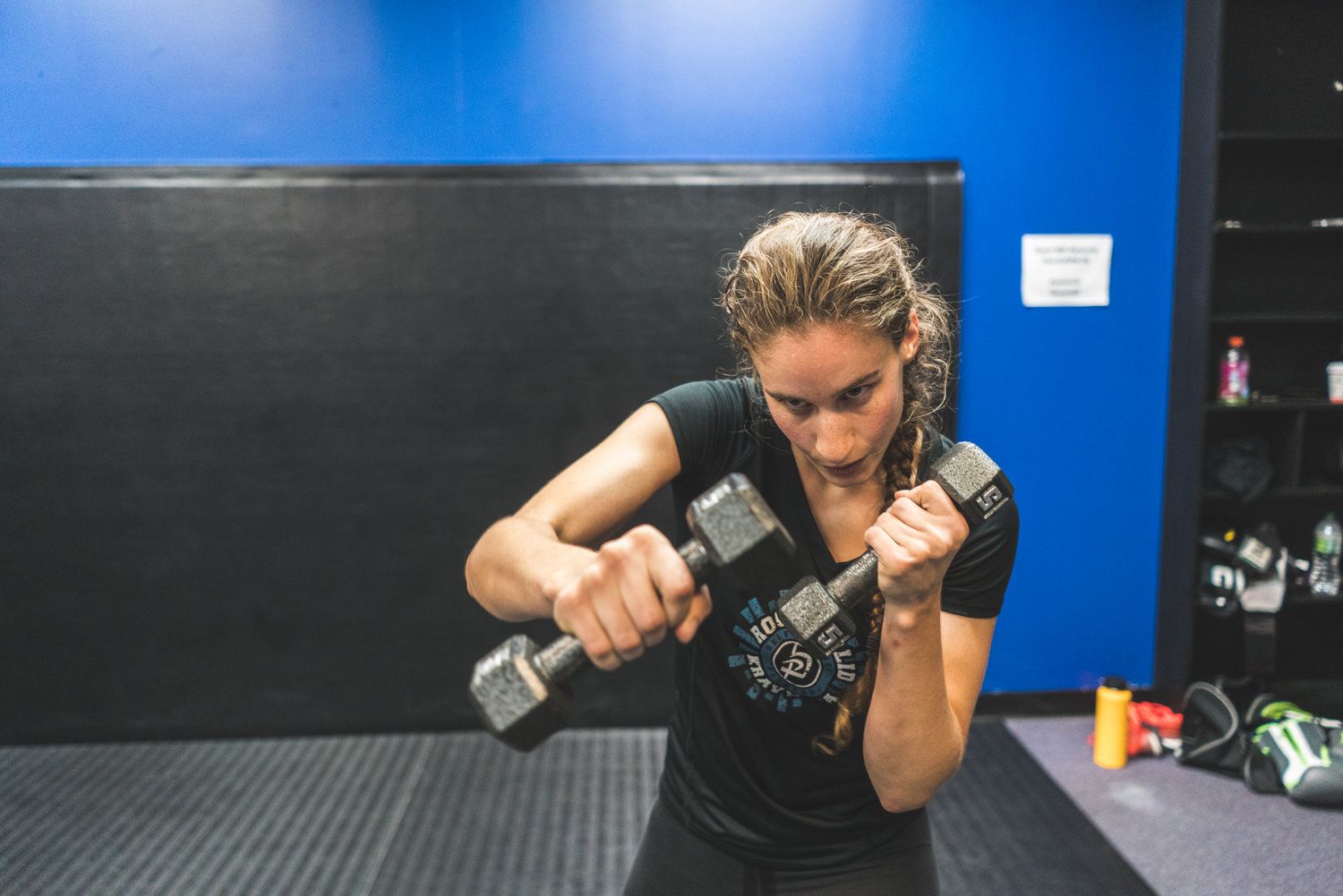 A woman is lifting a dumbbell in a gym.