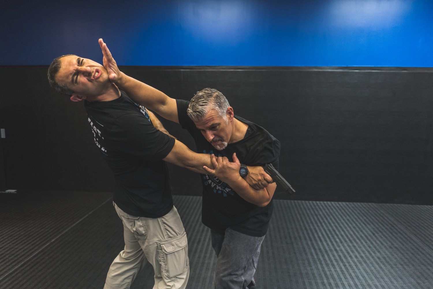 Two men are practicing martial arts in a gym.