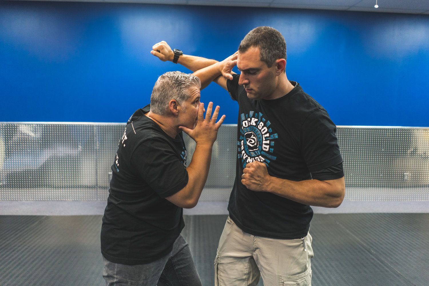 Two men are practicing martial arts in a gym.