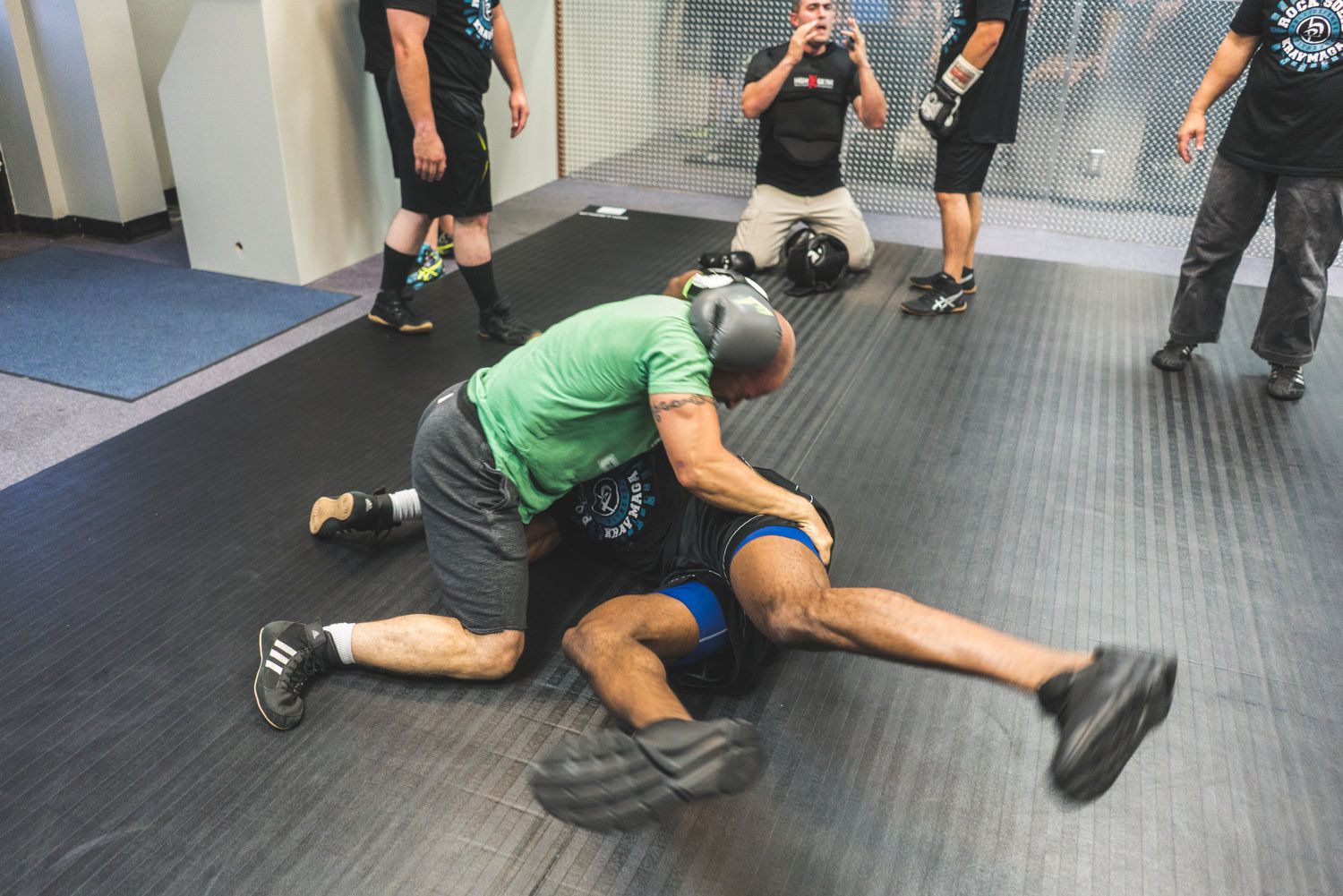 A group of men are wrestling on a mat in a gym.