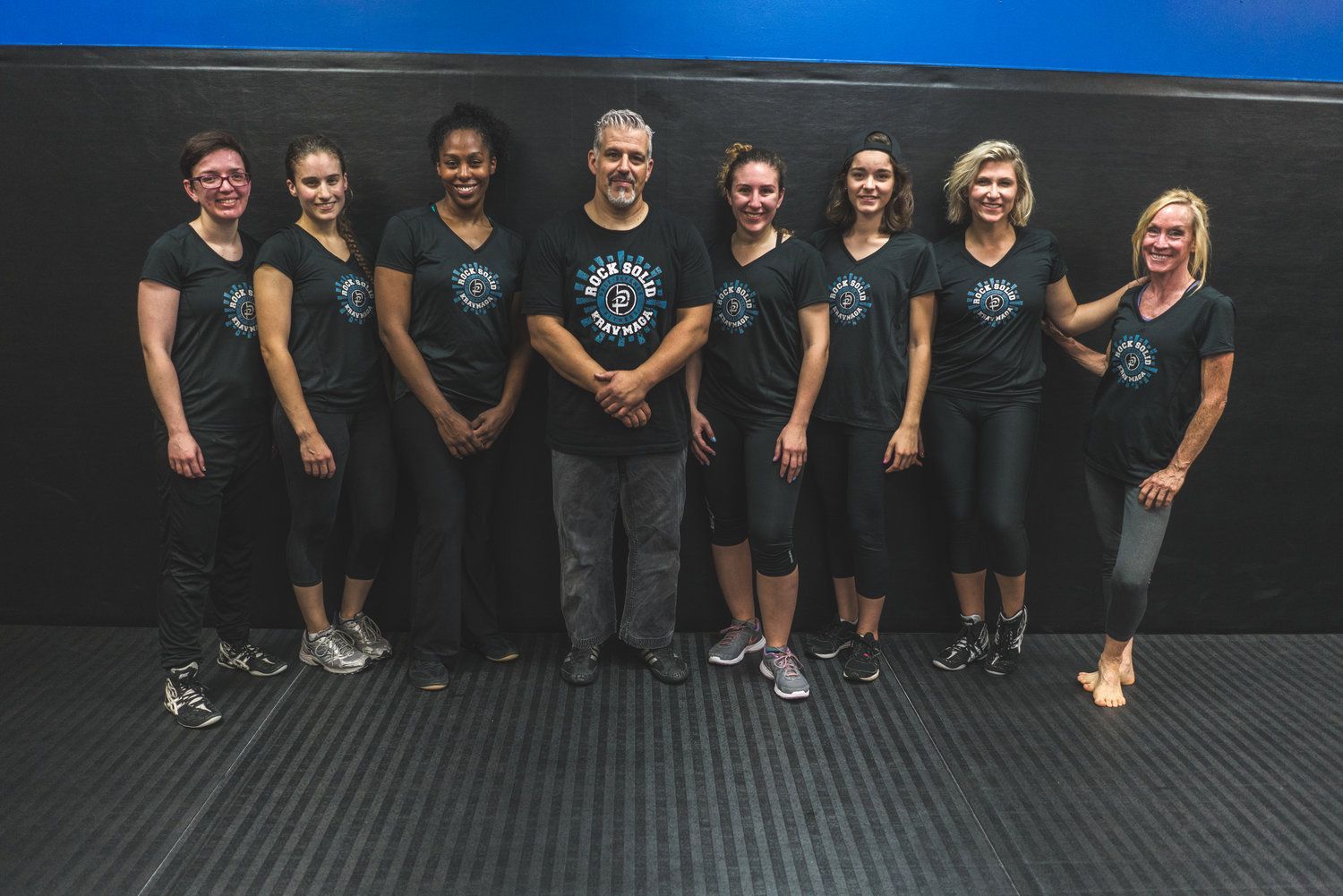 A group of people are posing for a picture in a gym.