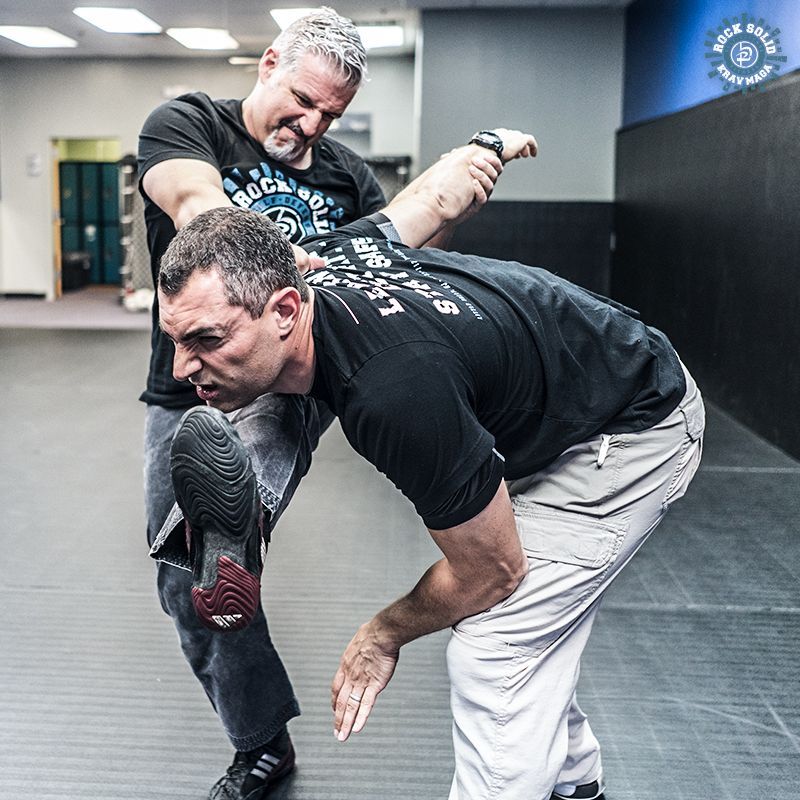 Two men are practicing martial arts in a gym.