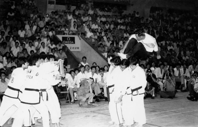 A group of people are performing martial arts in front of a crowd.