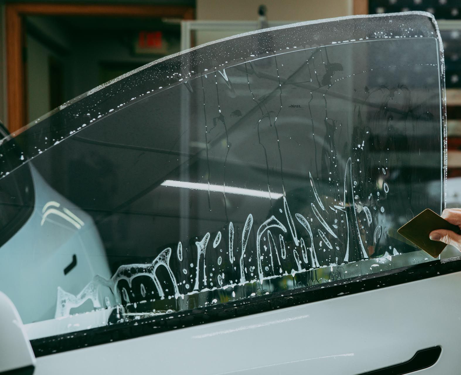 A person is cleaning a car windshield with a brush