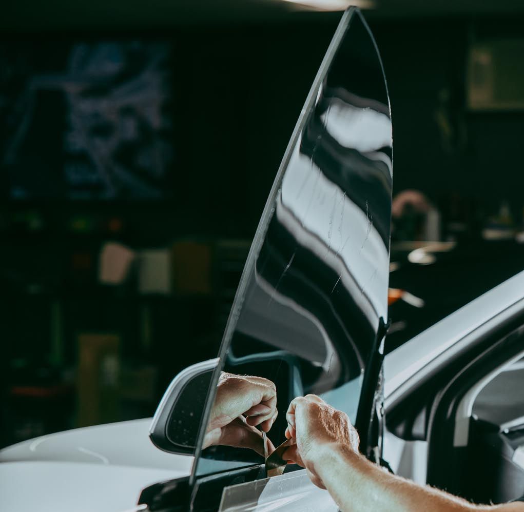 A person is fixing a car windshield with a tool.