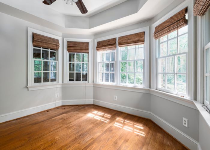 An empty room with a lot of windows and a ceiling fan.