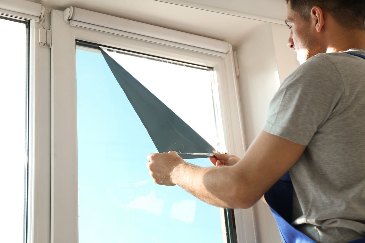 A man is installing a window film on a window.