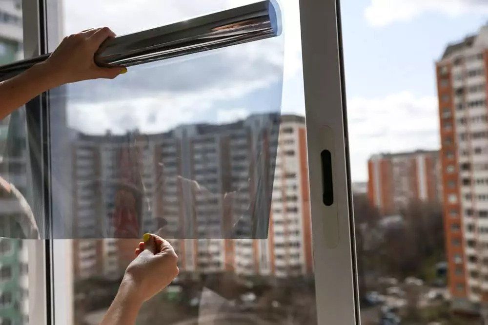 A person is installing a window film on a window.