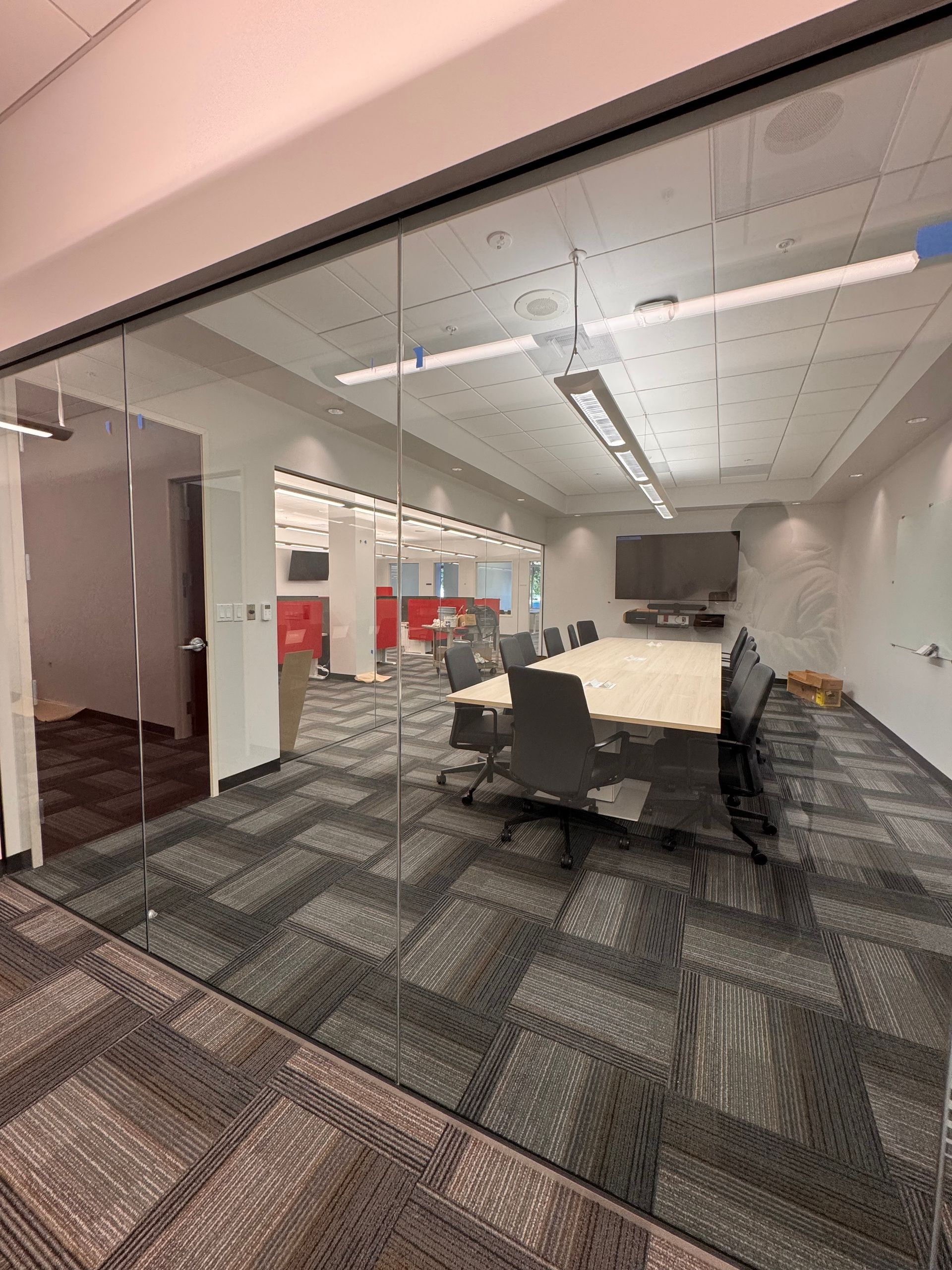 A conference room with a glass wall and a long table and chairs.