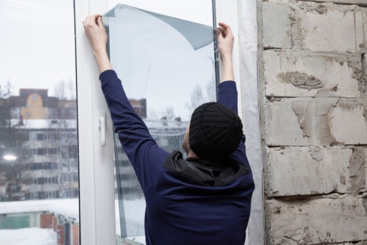 A man is installing a window film on a window.