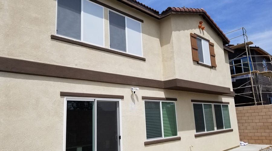 A house with a lot of windows and sliding glass doors is being built.