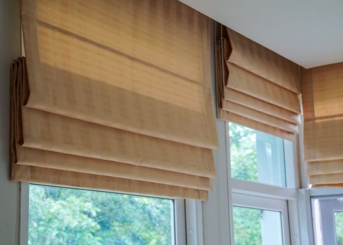 A close up of a window with roman shades on it