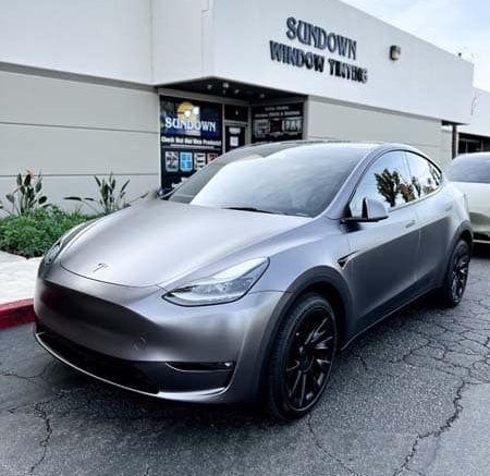 A tesla model y is parked in front of a building.