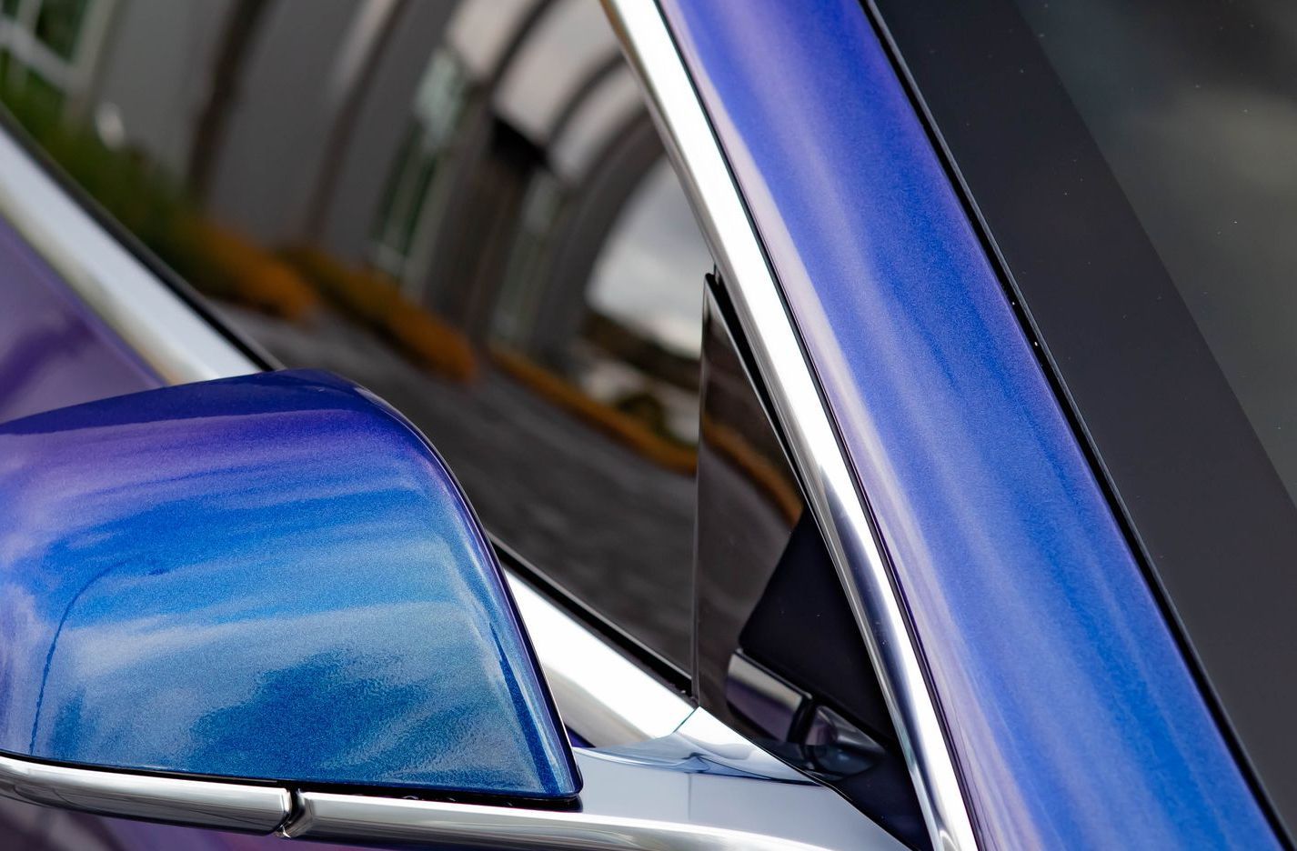 A blue tesla model s is on a black background.