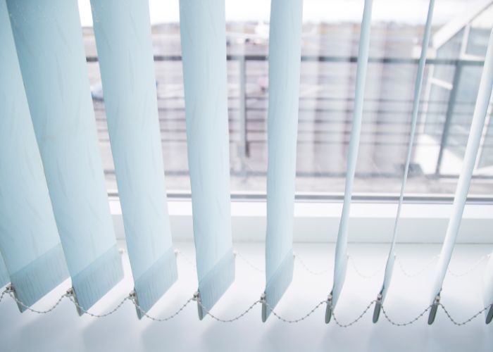 A close up of a window with vertical blinds on it.