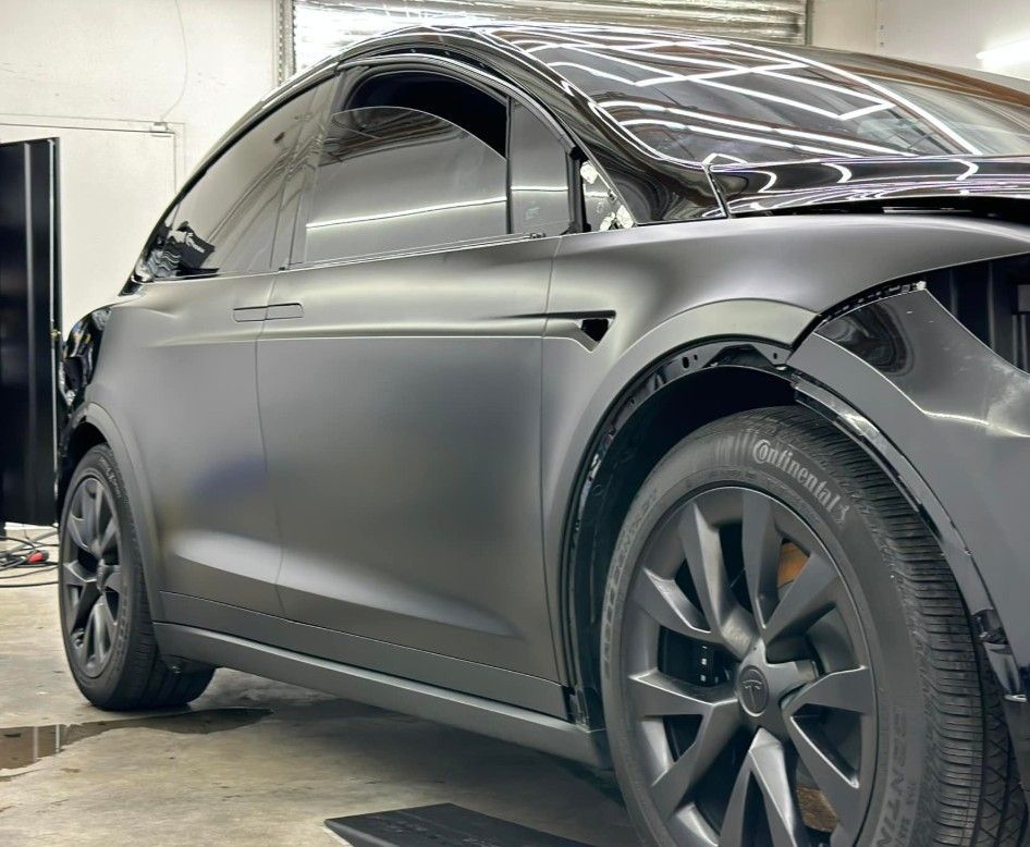 Black Tesla Model X with matte finish in a garage.