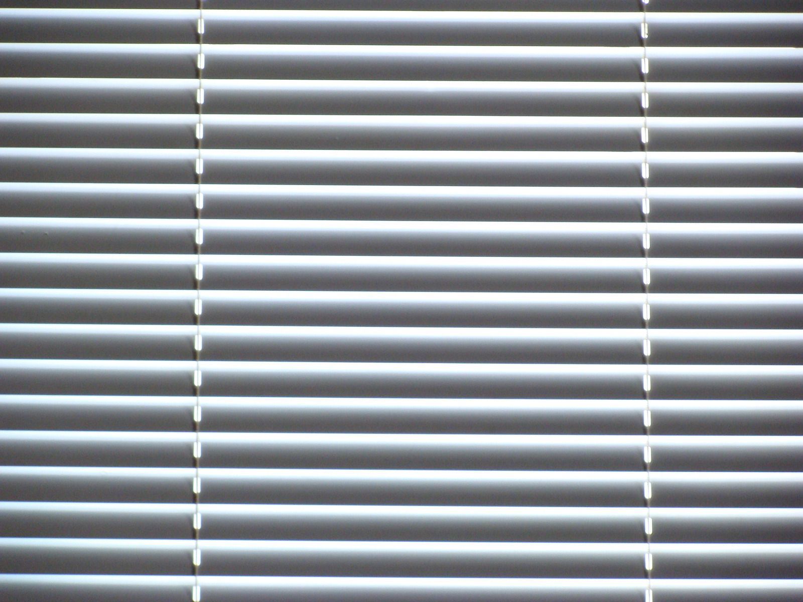 A close up of a pair of white blinds on a window.