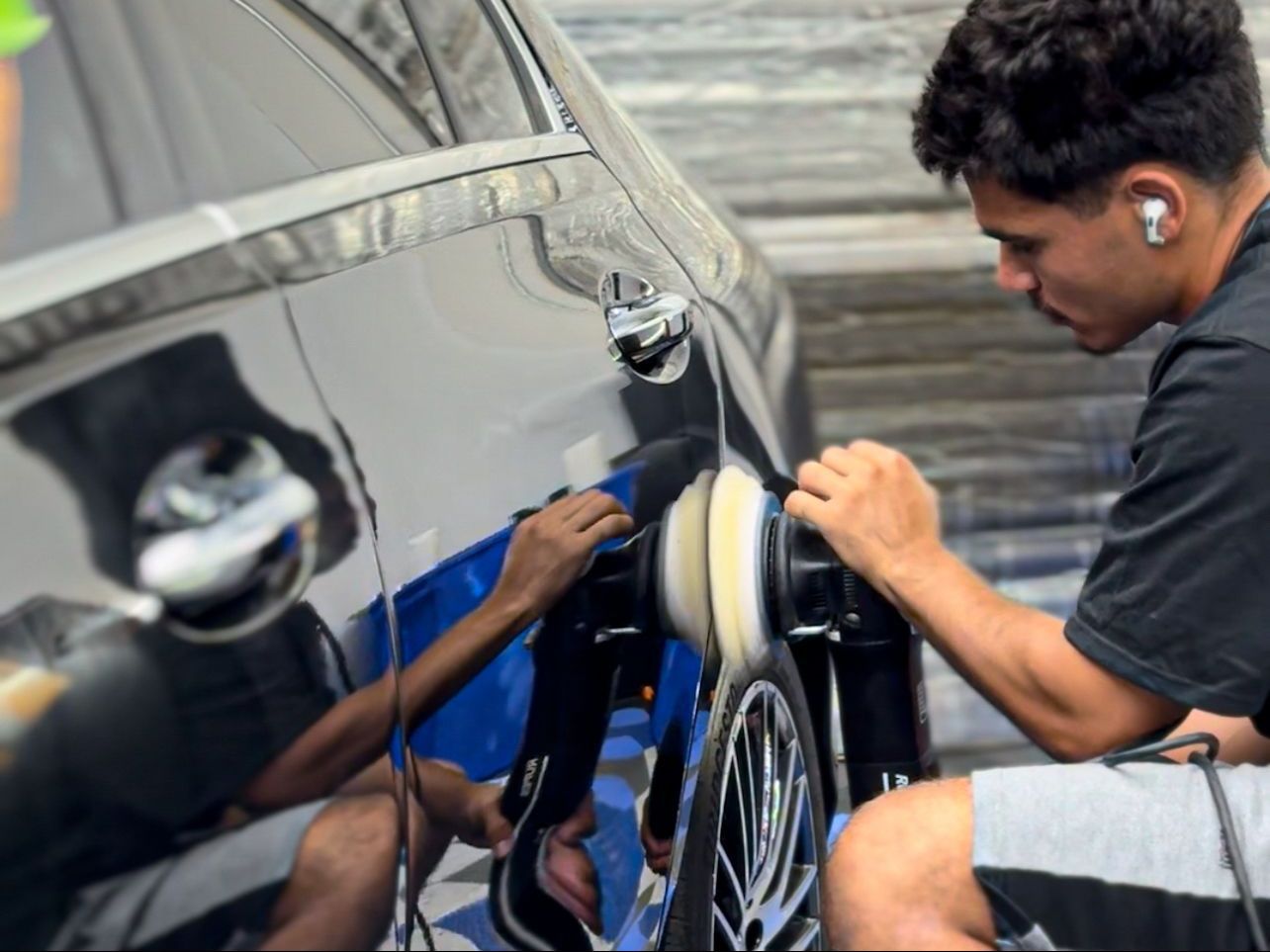 A man is polishing a car with a machine.