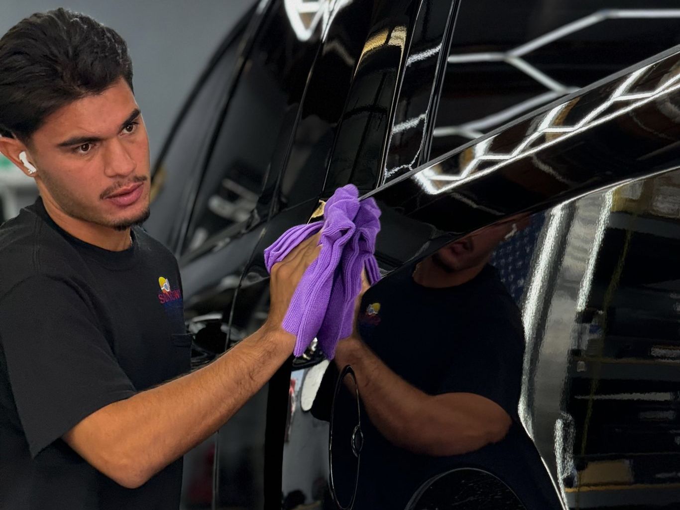 A man is cleaning a car with a purple cloth