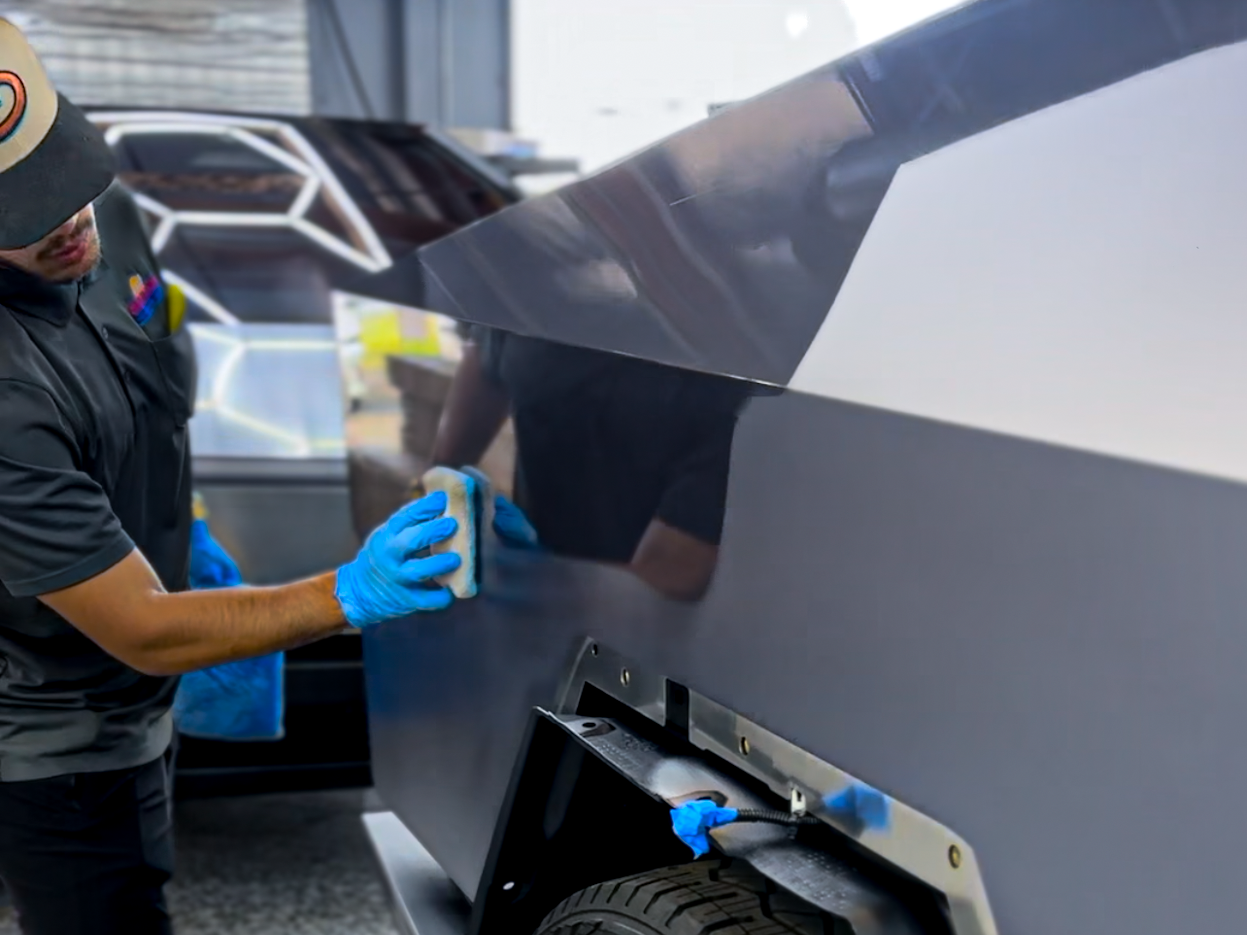 A man is cleaning the side of a car with a sponge.