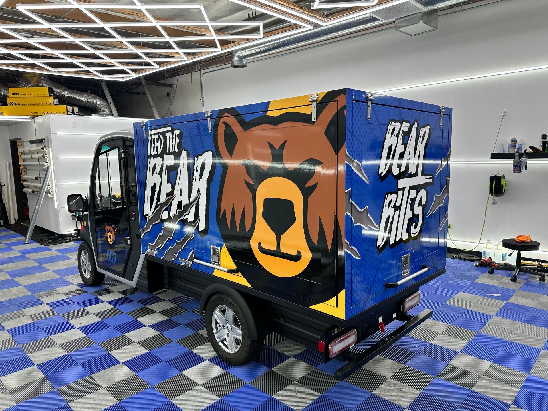 A blue truck with a bear on the side is parked in a garage.