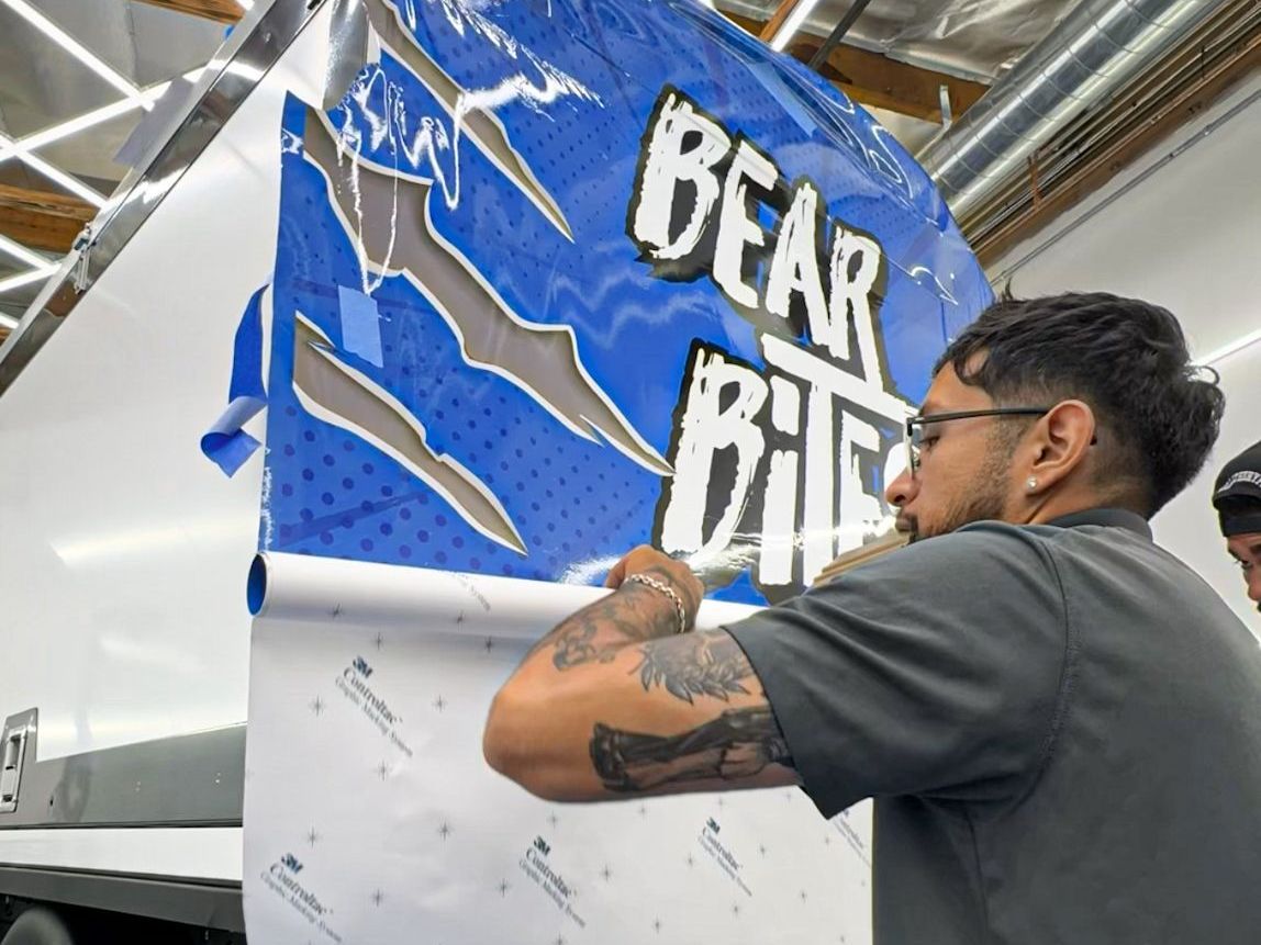 A man is wrapping a sign that says bear bite on it.