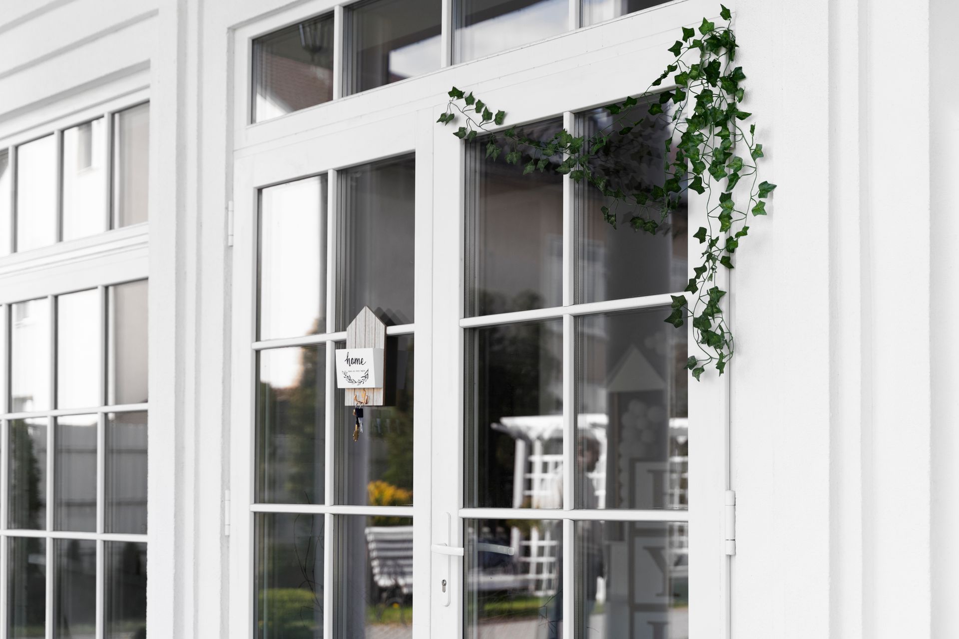 A white house with a lot of windows and ivy growing on the door.