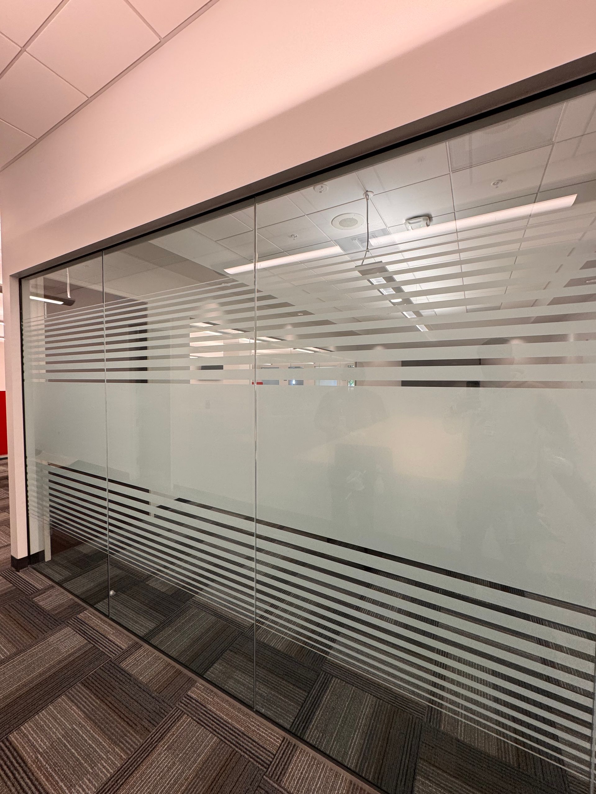 A glass wall with a striped design on it in an office.